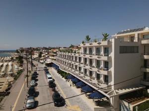 尼亚·卡利克拉提亚爱琴海蓝色海滩酒店 =的街边的建筑物享有街景,设有可停放的汽车