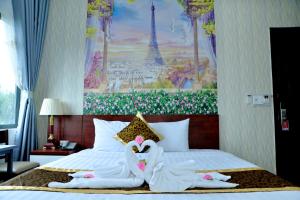 邦美蜀Buon Ma Thuot Hotel的一间卧室配有一张带两只天鹅的毛巾床