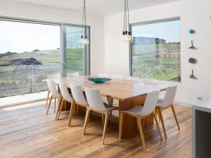 圣雷莫Ocean Breeze Now with 10 percent off over June July的一间带木桌和白色椅子的用餐室