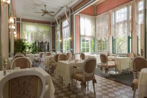蓬托德梅尔Belle Isle Sur Risle - Chateau Hotel & Spa的餐厅设有白色的桌椅和窗户。