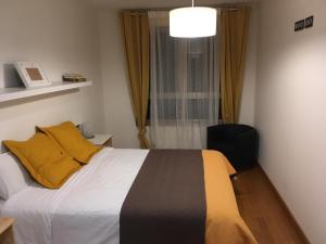 希洪Apartamento Playa Poniente的一间卧室配有一张带黄色枕头的床和一扇窗户
