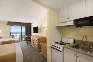 代托纳海滩热带海洋戴斯酒店的酒店客房设有厨房和带一张床的卧室