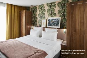 巴黎泰勒酒店的一间卧室配有一张带白色床单的大床