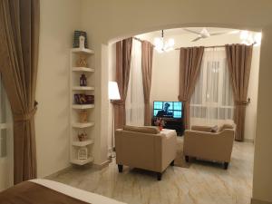 锡卜Muscat Royal Suites的客厅配有两把椅子和电视