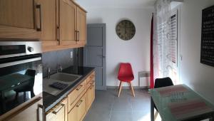 阿朗松LE PONT NEUF 61的厨房配有红色椅子和墙上的时钟