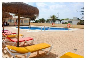 洛斯卡尼奥斯德梅卡Apartamentos Inma Mayor en primera línea de playa, con Parking y Piscina的一组椅子和遮阳伞,位于游泳池旁