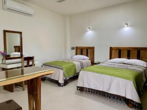 埃斯孔迪多港Lidxi Rosae的客房设有两张床、一张桌子和一面镜子。