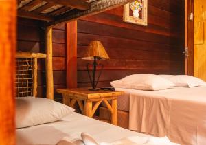阿布拉奥Lonier Nature INN的一间卧室设有两张床和一张桌子上的台灯。