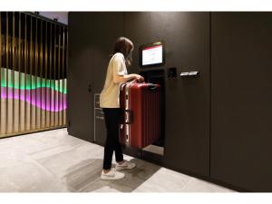 奈良Henn na Hotel Nara的一位女士在电梯里拉着一个红色的手提箱