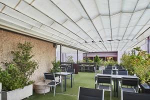 马德里西尔肯马德里之门酒店的一间设有桌椅的餐厅,种植了植物