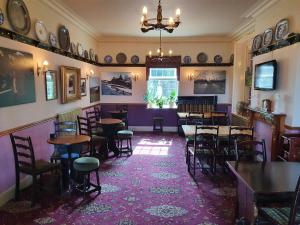 戈斯兰The Goathland Hotel的紫色墙壁内的餐厅,配有桌椅