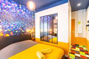 洛里昂SMILE APPARTS - Appartements - Au coeur de Lorient - Au calme - Tout Confort的一间卧室设有黄色的床和色彩缤纷的墙壁