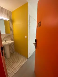 里尔Auberge de Jeunesse HI Lille的通往带水槽的浴室的橙色门
