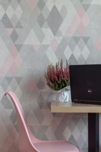 格但斯克INITIUM rooms - Pokoje na wynajem - Obrońców Wybrzeża 4D的一张带笔记本电脑和粉红色椅子的桌子