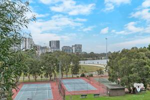 悉尼KOZYGURU WOLLI CREEK KOZY 1 BED APT SYDNEY AIRPORT & SYDNEY CBD NWC020的一组以城市为背景的网球场