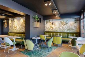 瓦卢瓦地区克雷皮Kyriad Crepy En Valois的餐厅设有桌椅,并画有棕榈树