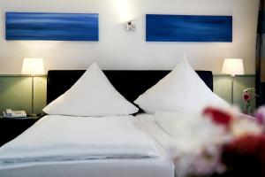 科隆库普菲克瑟尔酒店的酒店的客房内设有两张带白色枕头的床。