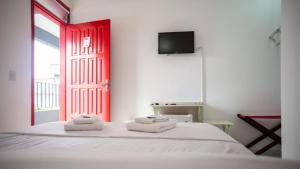 乌巴图巴Urbano Suítes的卧室配有白色的床和红色的门