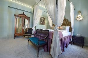 考纳斯Inner Blossom的一间卧室配有一张天蓬床、椅子和镜子