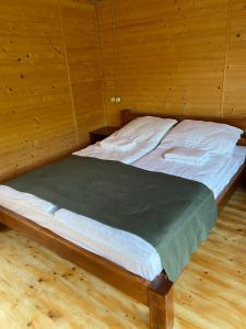 萨塔尼夫Готельний комплекс БУДИНОК РИБАКА的木墙客房的一张床位