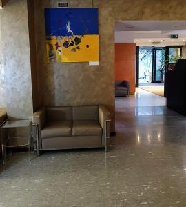 米兰梅特罗酒店的一间配有沙发的等候室和墙上的绘画