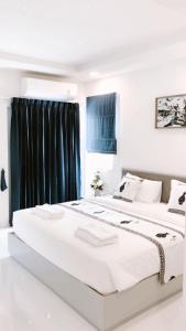 曼谷Icare Residence & Hotel的白色卧室设有两张床和黑色窗帘