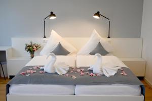 哈弗尔河畔勃兰登堡Hotel Brandenburger Dom的两个天鹅坐在床上,花香