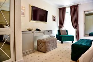 波尔Villa Giardino Heritage Boutique Hotel Bol的酒店客房设有电视和绿椅。