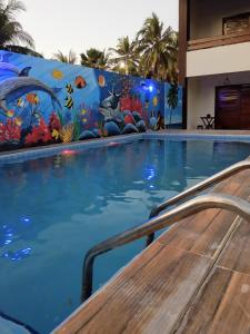 圣米格尔-杜斯米拉格里斯Pousada Paraíso dos Milagres的墙上挂有壁画的游泳池
