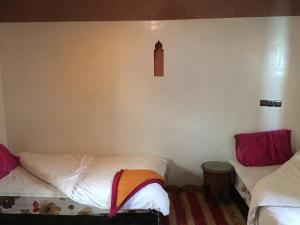 Aït ZiriMaison D'hôtes Dar Afra的客房设有两张床和带时钟的墙壁。