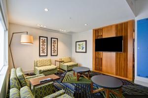 埃文斯维尔Holiday Inn Express - Evansville, an IHG Hotel的酒店客房设有沙发、椅子和平面电视。