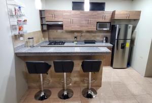 瓜亚基尔NCG SUITE SAMANES的厨房配有带冰箱和凳子的台面