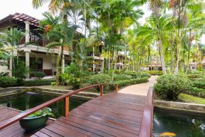 蔻立考拉克海湾度假酒店的通往带池塘的度假胜地的木制走道