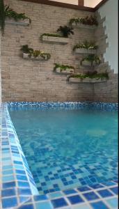 叶森图基Estet Hotel的砖墙前的蓝色瓷砖游泳池