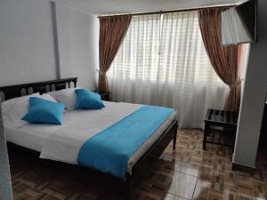 基多Val Hotel Santamaria Quito的一间卧室配有一张带蓝色枕头的床和一扇窗户。