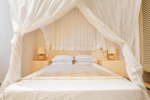 赫索尼索斯洛卡斯缇别墅酒店的卧室配有带白色床单和枕头的天蓬床。