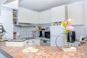 CheminotUne HALTE Quelque PART的厨房配有白色橱柜和花瓶,位于柜台上