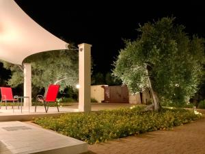 普蒂尼亚诺Tra gli ulivi的花园中晚上有两把红色椅子和一棵树