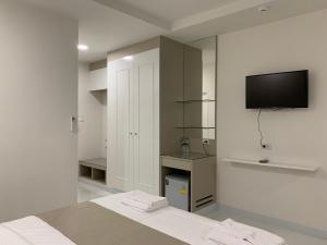 曼谷Icare Residence & Hotel的白色的房间,墙上配有电视