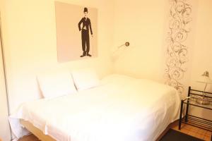 翁德洛FeWo Katharina (Teestube Undeloh) Lüneburger Heide的卧室配有白色的床,还展示了一张男人的照片