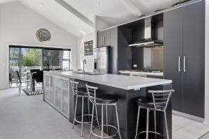陶波Bay Bliss - Lake Taupo Holiday Home的厨房配有黑色橱柜和带吧台凳的台面