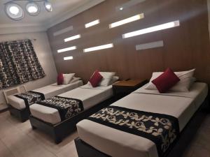 马尼拉Jupiter Suites的酒店客房,配有3张带红色枕头的床