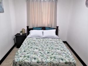 阿拉胡埃拉Kubo Apartment Private 2 Bedrooms 5 mins SJO Airport with AC的一间卧室配有一张带绿色和白色棉被的床