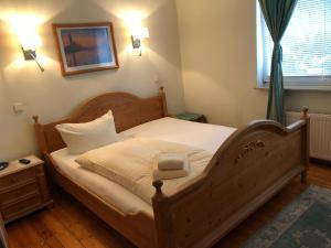 柏林豪斯比尔克膳食公寓酒店的一间卧室配有一张带白色床单的木床