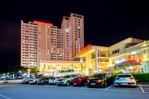土龙木市Becamex Hotel Thu Dau Mot的停车场,停车场的汽车停在大楼前