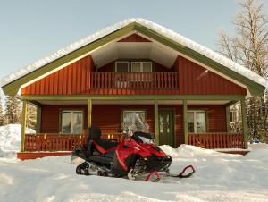 基律纳Camp Alta Kiruna的停在房子前雪地里的摩托车