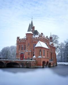 布鲁日Castle ten Berghe Château的一座大型红砖建筑,水中有一桥