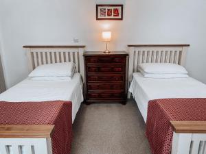 伍德斯托克布伦海姆巴特利酒店的一间卧室配有两张床和一个带灯的梳妆台。