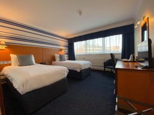 利物浦斯特林利物浦莱纳酒店的酒店客房设有两张床、一张桌子和一台电视。