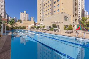 圣保罗圣保罗奥林匹亚美居别墅酒店的一座大型游泳池旁设有椅子和遮阳伞